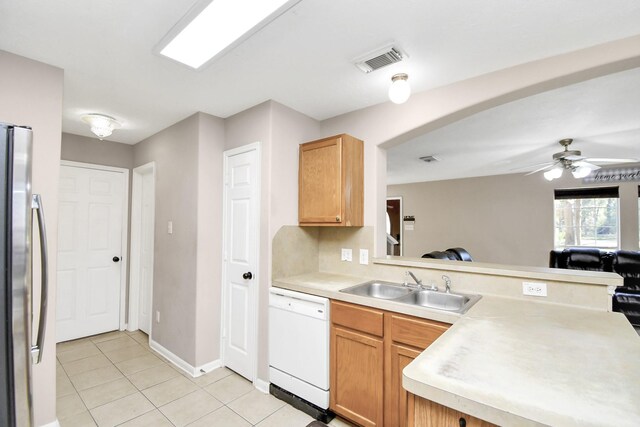 kitchen with white dishwasher, sink, ceiling fan, light tile patterned floors, and stainless steel refrigerator