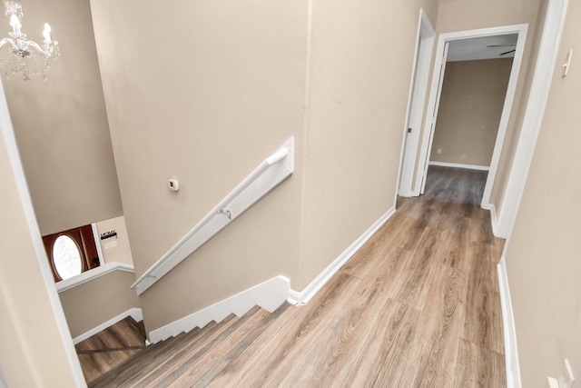 hallway with light hardwood / wood-style flooring and an inviting chandelier