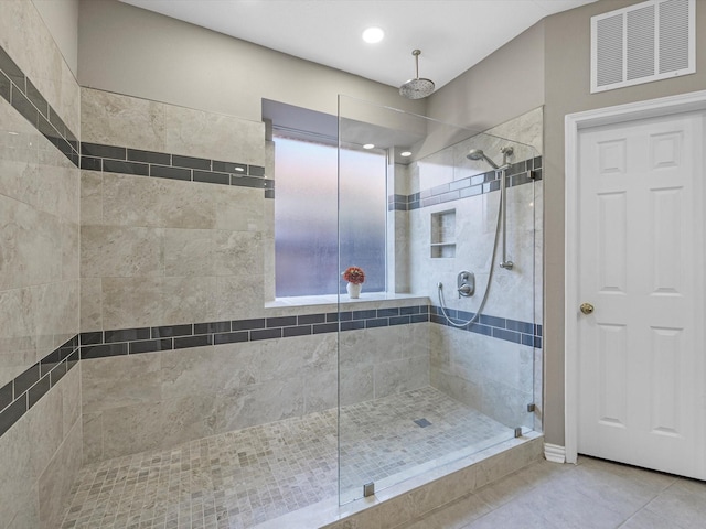 bathroom featuring tiled shower, tile patterned flooring, and a healthy amount of sunlight