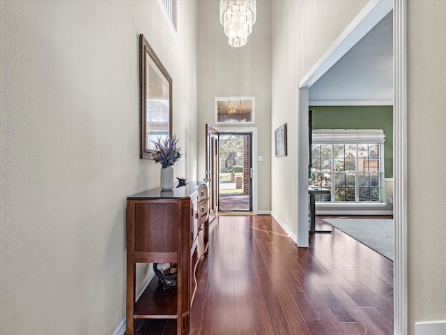 entryway with ornamental molding, dark wood-type flooring, and an inviting chandelier