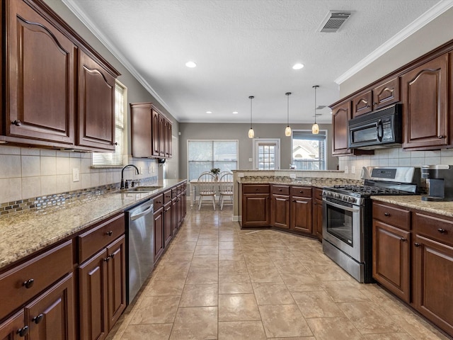 kitchen featuring decorative light fixtures, sink, ornamental molding, and stainless steel appliances