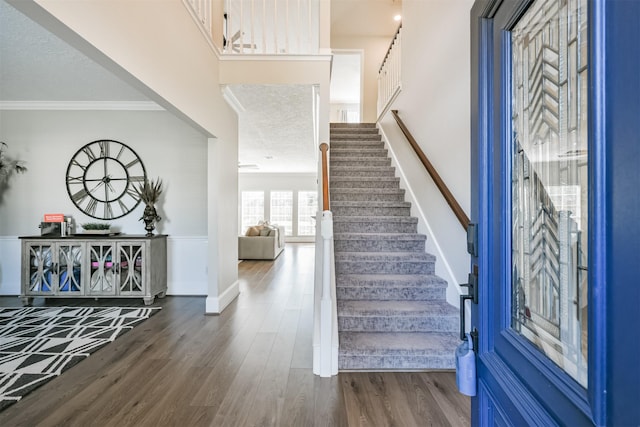 entrance foyer with dark wood-type flooring, a textured ceiling, and ornamental molding