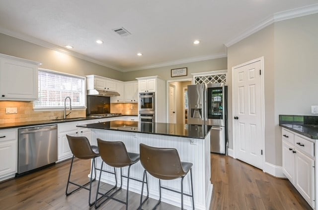 kitchen featuring appliances with stainless steel finishes, dark hardwood / wood-style floors, white cabinetry, and a kitchen island