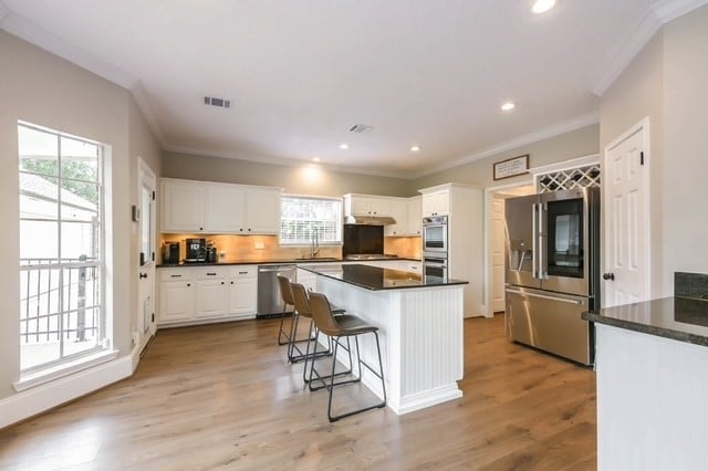 kitchen with white cabinetry, crown molding, stainless steel appliances, and light wood-type flooring