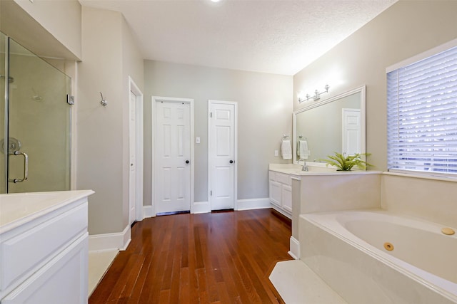 bathroom featuring hardwood / wood-style floors, vanity, a textured ceiling, and plus walk in shower