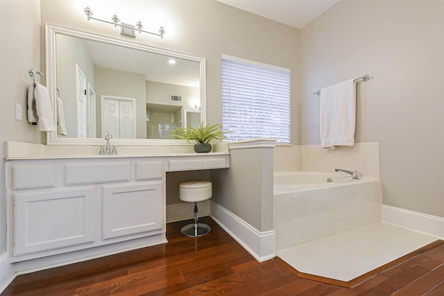 bathroom with a tub to relax in, vanity, and wood-type flooring