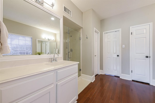 bathroom with hardwood / wood-style floors, vanity, and walk in shower