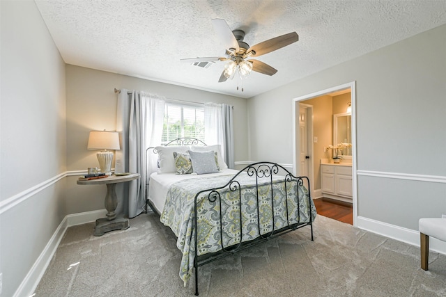 bedroom with connected bathroom, ceiling fan, carpet, and a textured ceiling