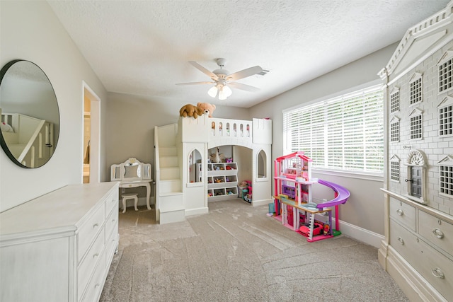 recreation room with ceiling fan, light colored carpet, and a textured ceiling