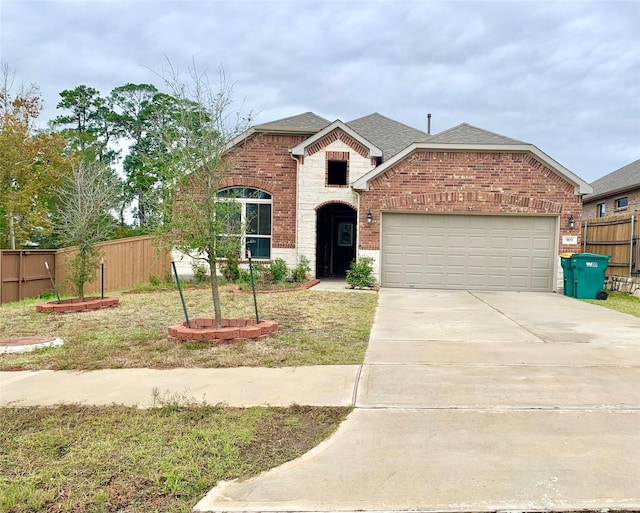 traditional home featuring an attached garage, brick siding, fence, concrete driveway, and roof with shingles