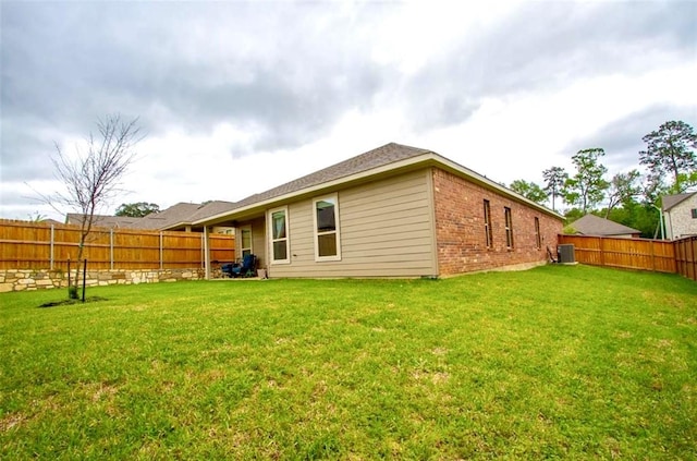 rear view of house with a fenced backyard, central AC, a lawn, and brick siding