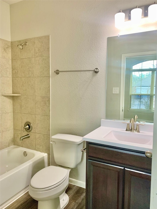 bathroom featuring baseboards, toilet, wood finished floors, vanity, and shower / washtub combination