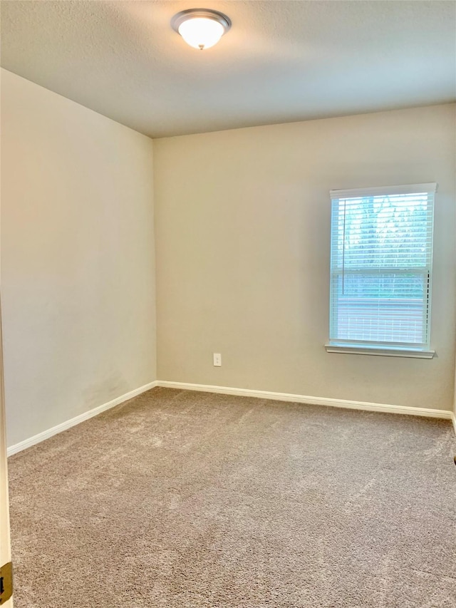 empty room featuring carpet, a textured ceiling, and baseboards