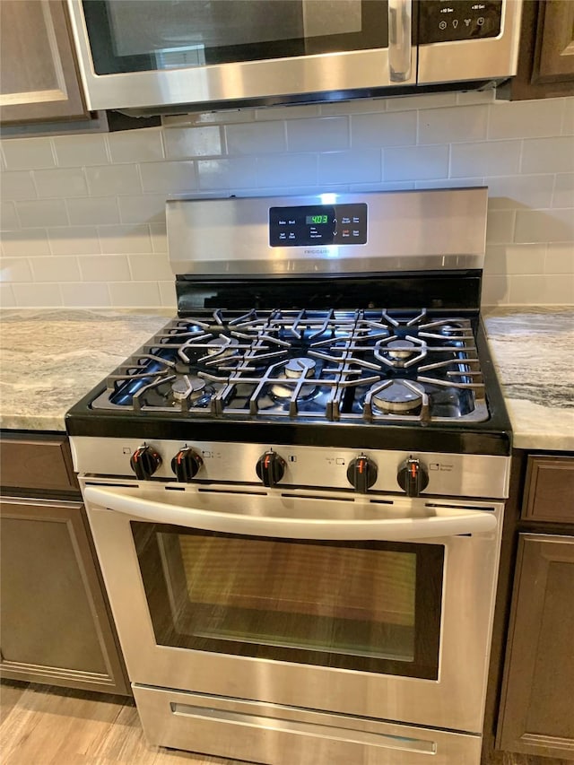 room details featuring appliances with stainless steel finishes, light stone counters, and tasteful backsplash