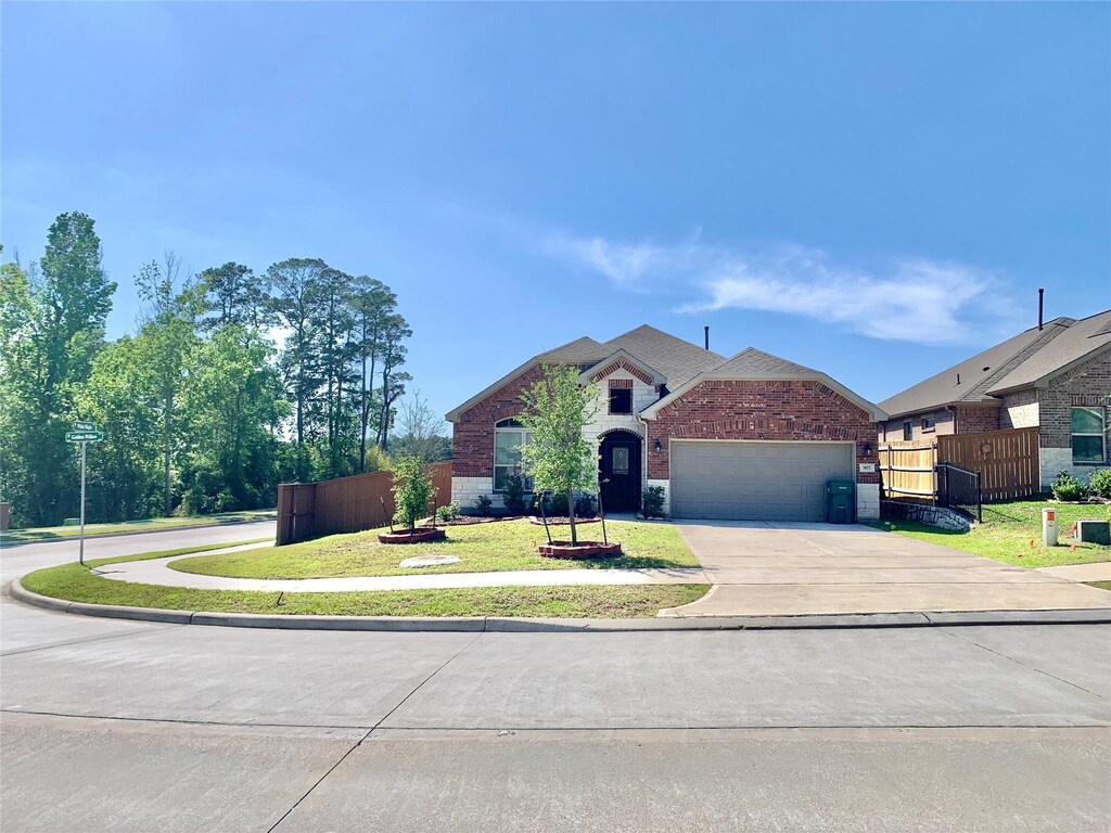 907 Golden Willow Ln, Conroe, TX 77304 - view of front of house with driveway, an attached garage, a front yard, brick siding, and fence