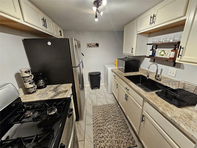 kitchen with light stone countertops, sink, black range with gas stovetop, cream cabinets, and washer / dryer