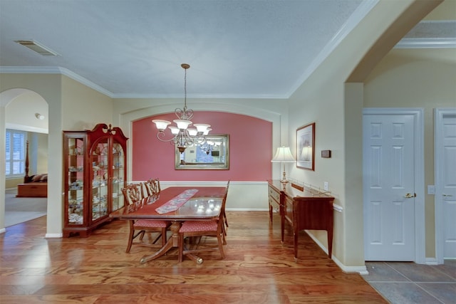 dining room with hardwood / wood-style flooring, crown molding, and a notable chandelier