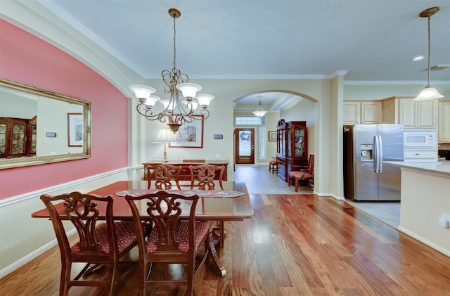 dining space featuring light hardwood / wood-style floors, ornamental molding, and a chandelier