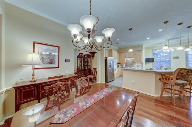 dining space with ornamental molding, light hardwood / wood-style flooring, a chandelier, and sink