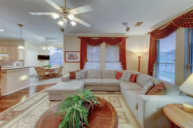 living room with light wood-type flooring, ceiling fan, and ornamental molding