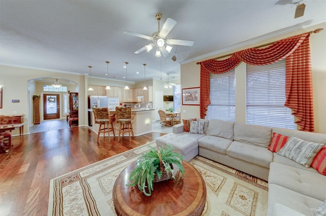 living room with ceiling fan, wood-type flooring, and ornamental molding