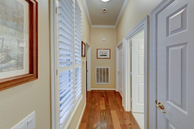 hallway featuring light wood-type flooring, plenty of natural light, and crown molding