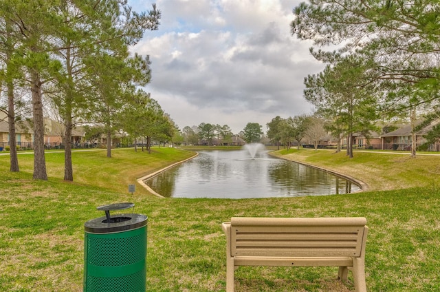 view of property's community with a water view and a lawn