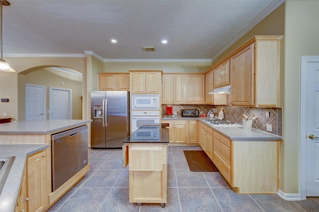 kitchen with decorative backsplash, appliances with stainless steel finishes, light brown cabinetry, decorative light fixtures, and a kitchen island