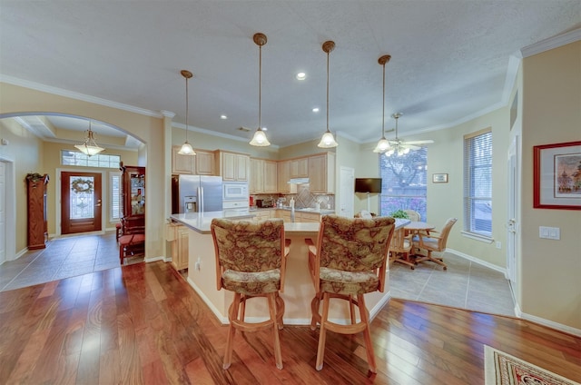 kitchen with stainless steel fridge, crown molding, pendant lighting, light hardwood / wood-style floors, and white microwave