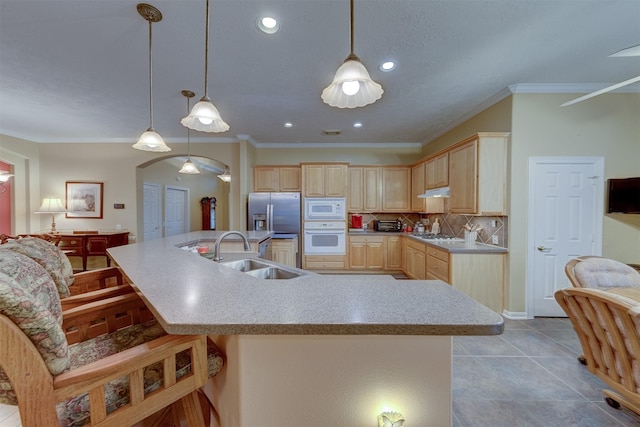 kitchen featuring sink, light brown cabinets, hanging light fixtures, tasteful backsplash, and white appliances