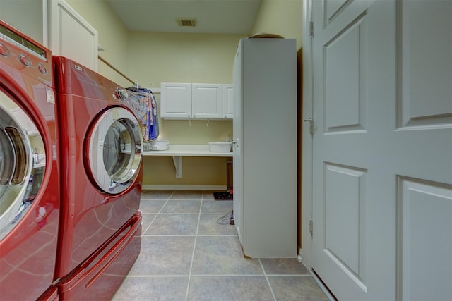 laundry area with washing machine and clothes dryer, light tile patterned floors, and cabinets