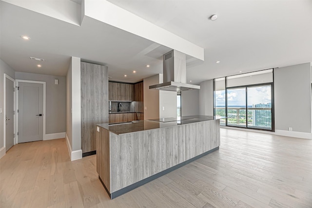 kitchen featuring black electric stovetop, a kitchen island, light wood-type flooring, and island exhaust hood