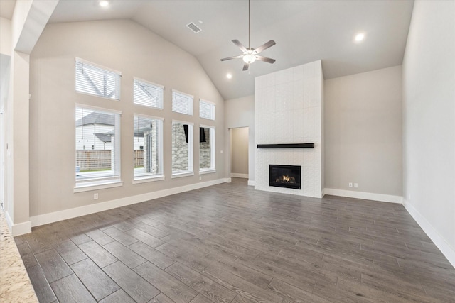 unfurnished living room with a fireplace, a towering ceiling, and ceiling fan