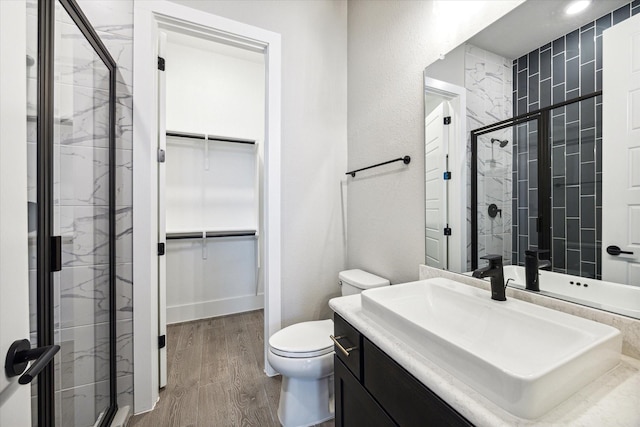 bathroom featuring vanity, wood-type flooring, a shower with shower door, and toilet