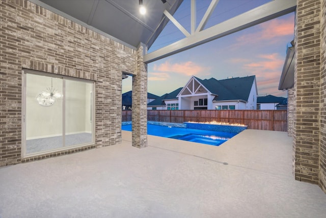 pool at dusk featuring an in ground hot tub and a patio