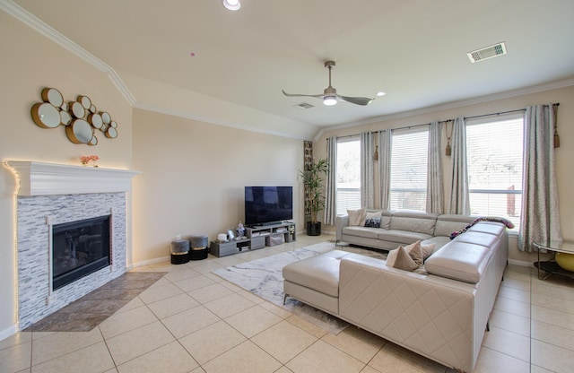 tiled living room featuring ceiling fan, a stone fireplace, ornamental molding, and vaulted ceiling