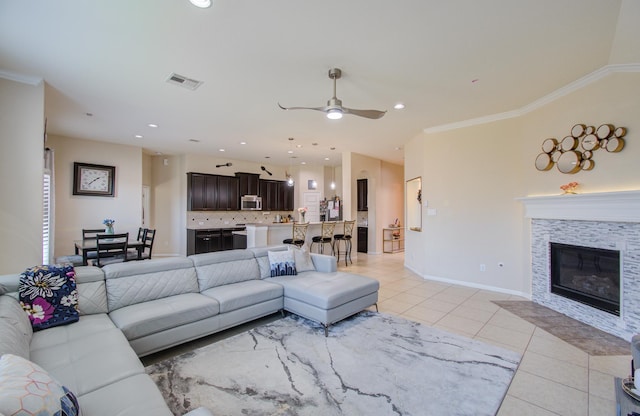 living room with ceiling fan, ornamental molding, and light tile patterned floors