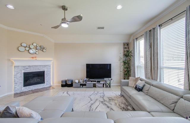 tiled living room with a stone fireplace, crown molding, plenty of natural light, and ceiling fan