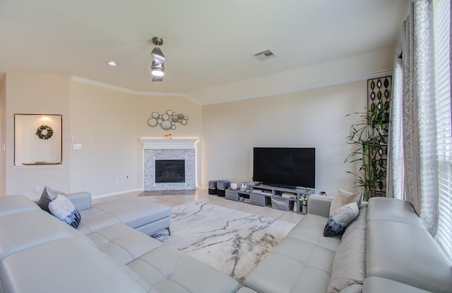 living room with a stone fireplace, light tile patterned floors, and ornamental molding