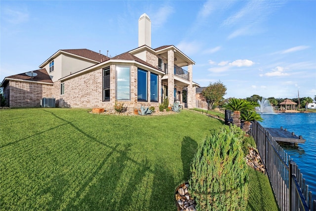 rear view of property featuring cooling unit, a water view, a yard, and a balcony