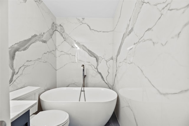 bathroom featuring a bath, vanity, toilet, and tile walls