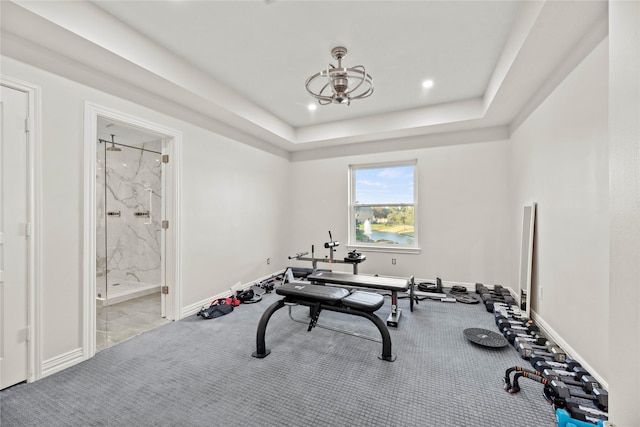 workout area with a raised ceiling and light carpet