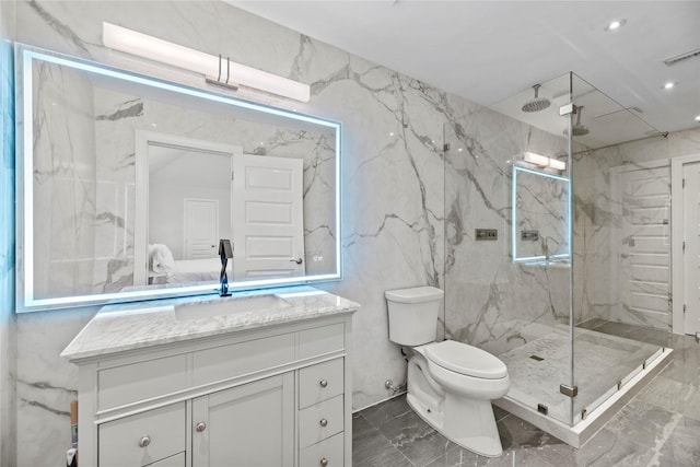 bathroom featuring vanity, toilet, a shower with shower door, and tile walls