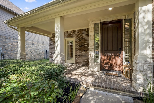 doorway to property with brick siding and a porch