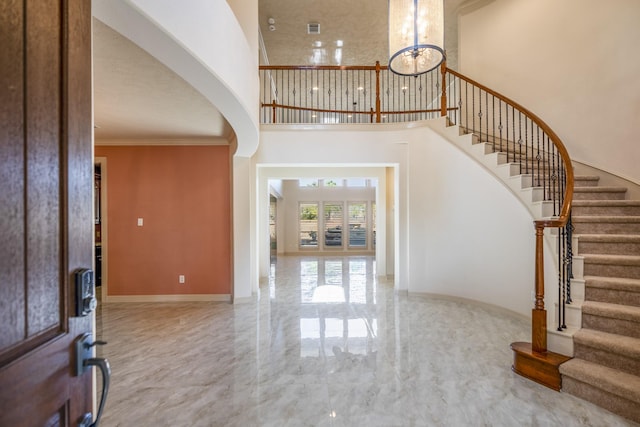 foyer with baseboards, ornamental molding, marble finish floor, a high ceiling, and stairs