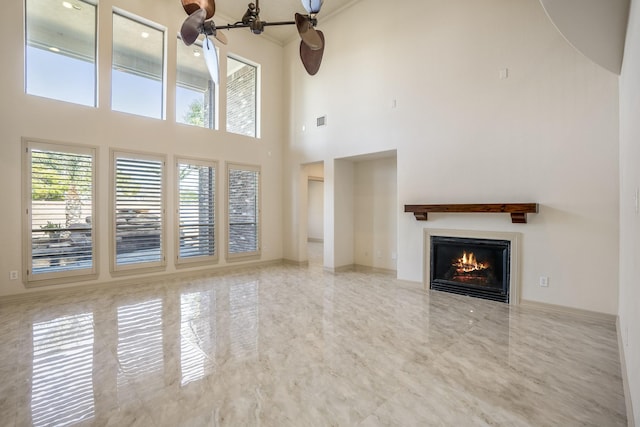 unfurnished living room featuring marble finish floor, a lit fireplace, a high ceiling, and visible vents