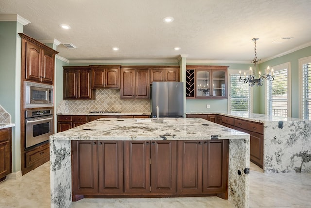 kitchen with visible vents, an island with sink, glass insert cabinets, stainless steel appliances, and a sink