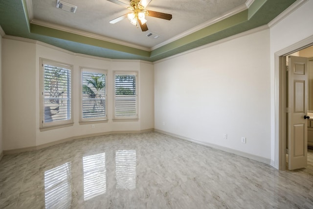 spare room with ornamental molding, a tray ceiling, and visible vents