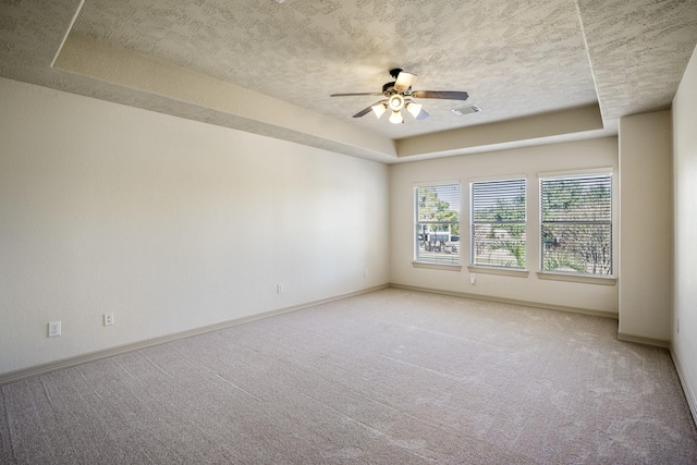 unfurnished room with light carpet, a raised ceiling, a ceiling fan, and baseboards