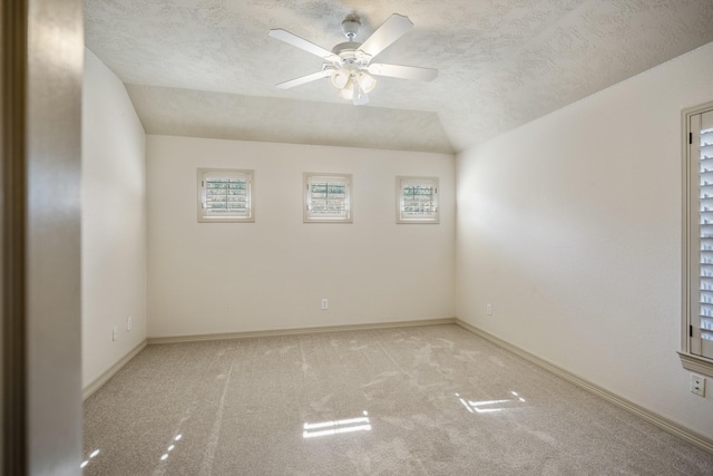 unfurnished room featuring carpet, baseboards, lofted ceiling, and a textured ceiling